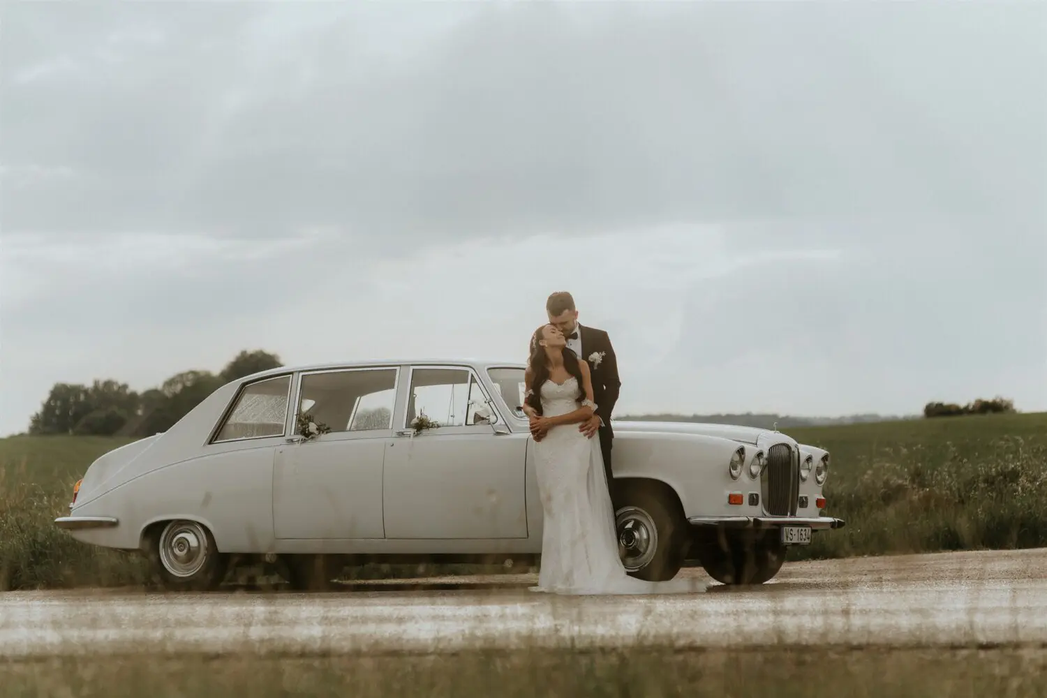 1983. gada Daimler DS-420 limuzīns kāzu transporta vizualizācijā. Attēlā redzams elegants, gaišs retro limuzīns ar romantiskiem ziedu dekoriem uz logiem